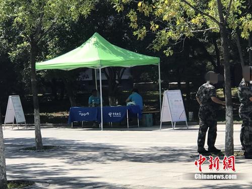 中國電信在某高校內擺攤出售手機卡，旁邊就是正在軍訓的學生。中新網 吳濤 攝