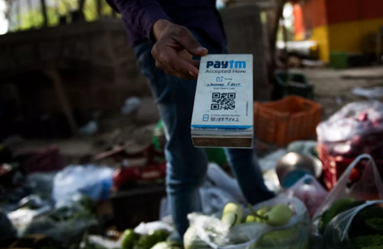 2017年4月12日，在印度新德里街頭，一名蔬菜攤主手持Paytm二維碼接受電子支付。印度Paytm在支付寶母公司螞蟻金服的支持下，已經成為印度最大的移動支付平台。新華社記者畢曉洋攝