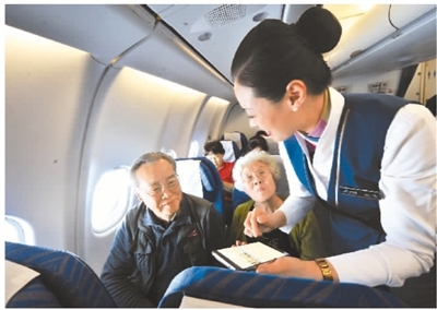 2018年1月18日開始，根據民航總局的規定，航空乘客可以在飛機上使用手機。圖為航空人員在幫助乘客使用手機上網。 楚洪雨攝（人民圖片）